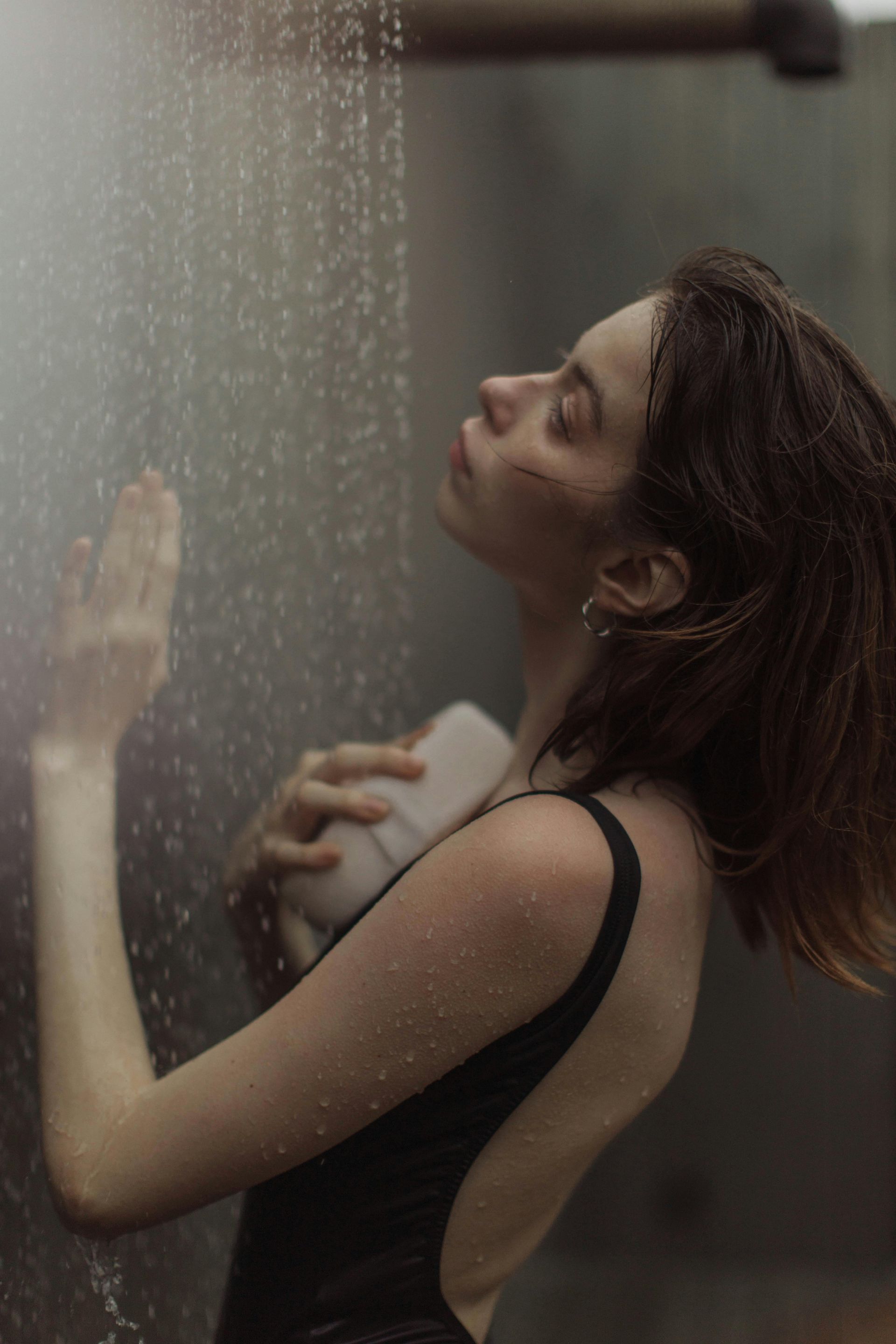 A woman in a black swimsuit is taking a shower.