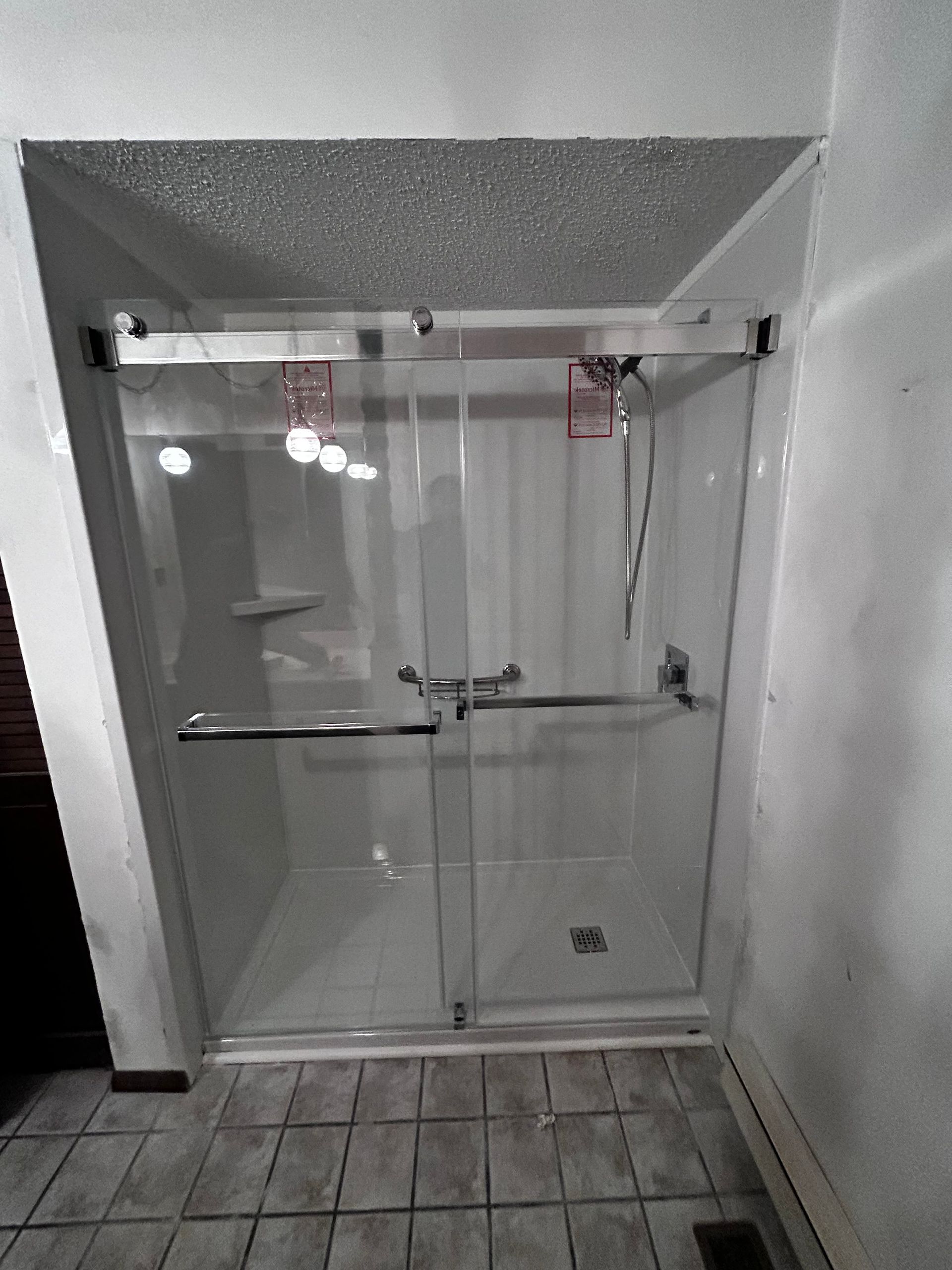 A bathroom with a sliding glass shower door and a tiled floor.