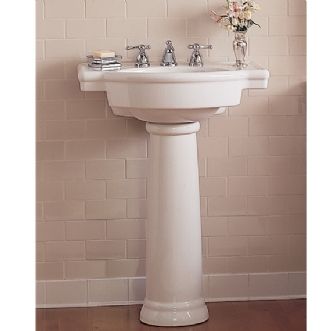 A white pedestal sink in a bathroom with a vase of flowers on top of it.