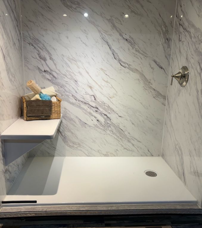 A bathroom with marble walls and a walk in shower.