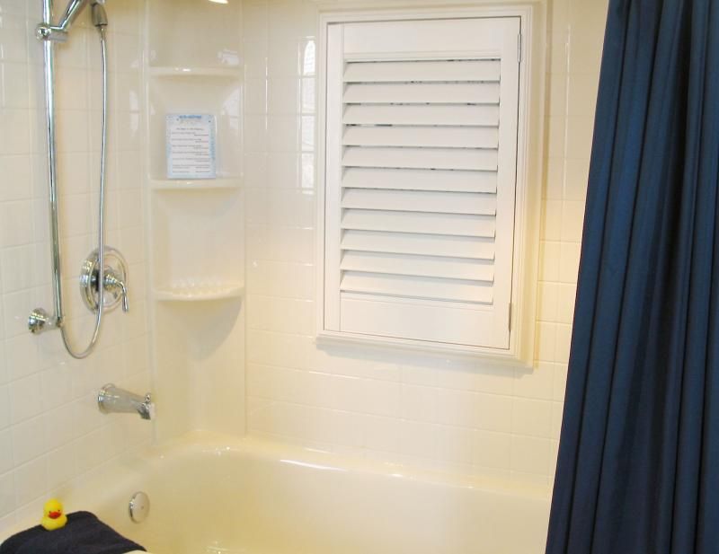 A bathtub with a blue shower curtain and a shower head
