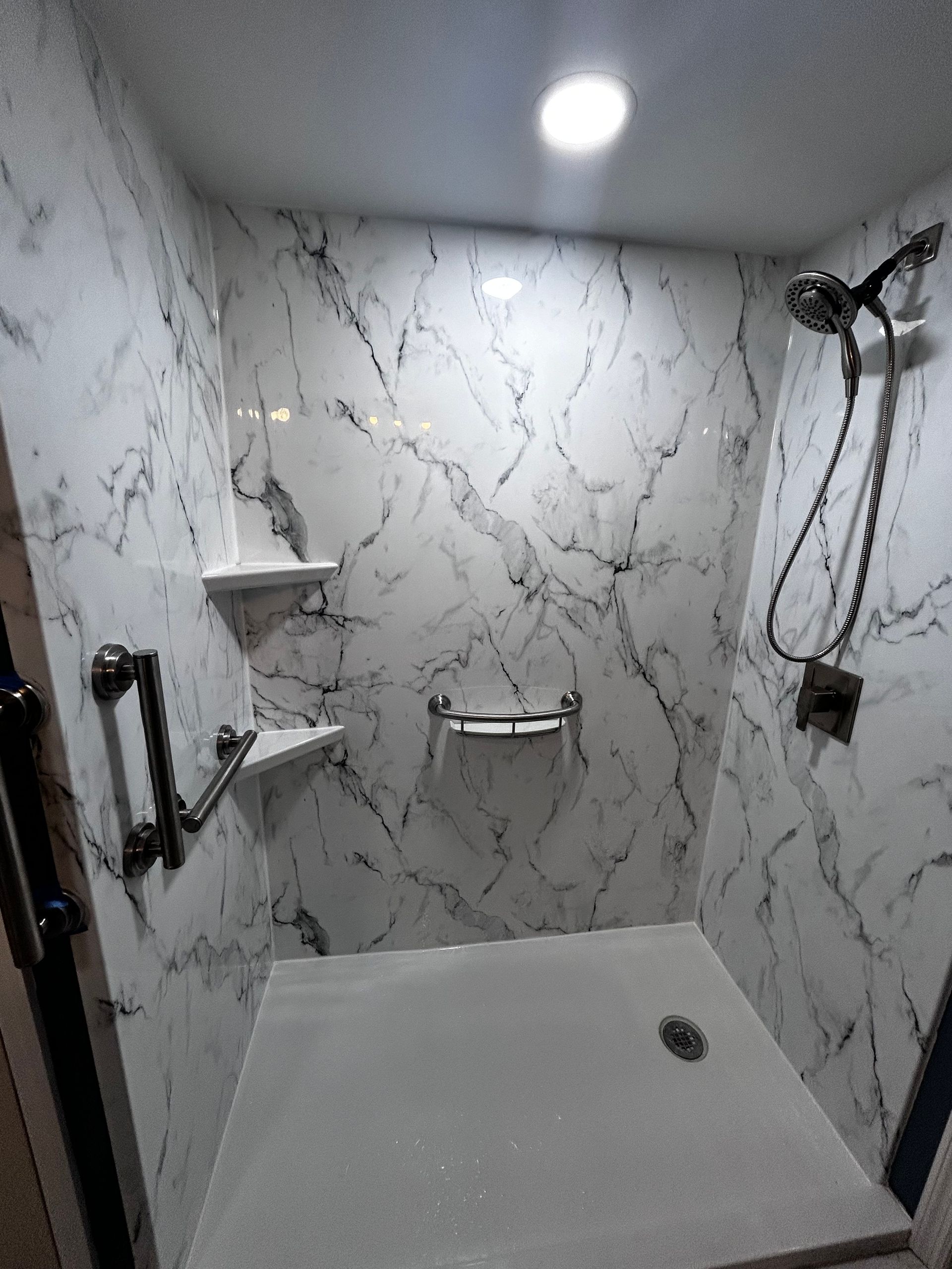 A shower with marble walls and a shower head.