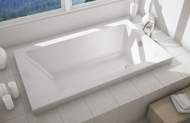 A white bathtub is in a bathroom next to a window.