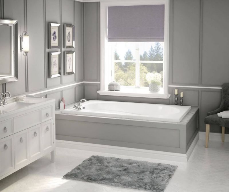 A bathroom with a tub , sink , mirror and chair.