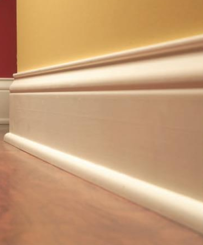 A close up of a white molding on a wooden floor in a room.