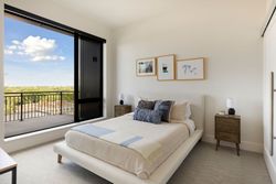 Bedroom with bed, nightstands, large window with view, and artwork on the wall.