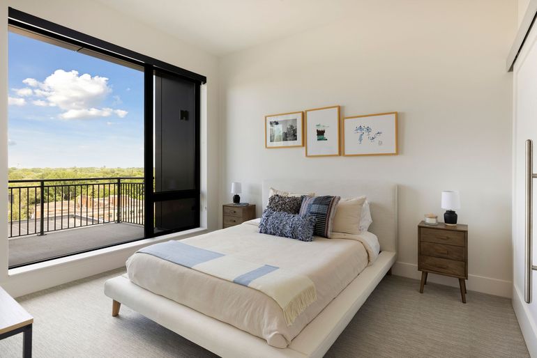 Bedroom with bed, nightstands, large window with a view, and artwork.