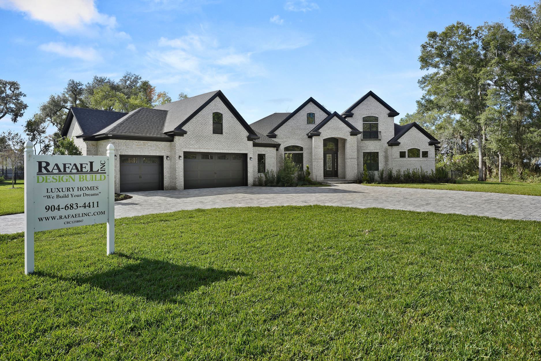 A large house with two garages is sitting on top of a lush green field.