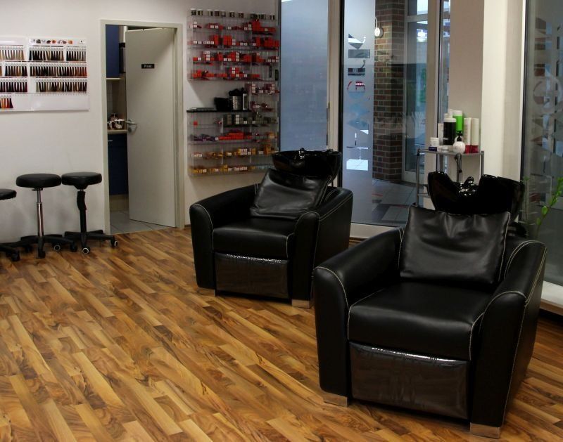 Ein Salon mit zwei schwarzen Stühlen und einem Waschbecken