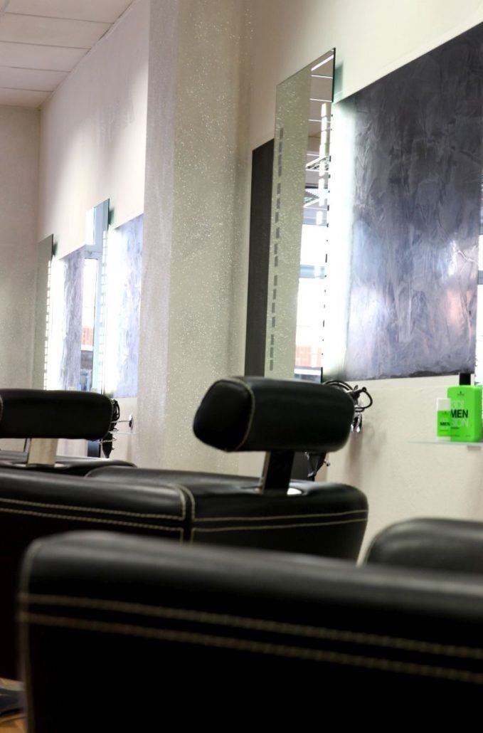 Eine Stuhlreihe in einem Friseursalon mit einem Spiegel an der Wand.