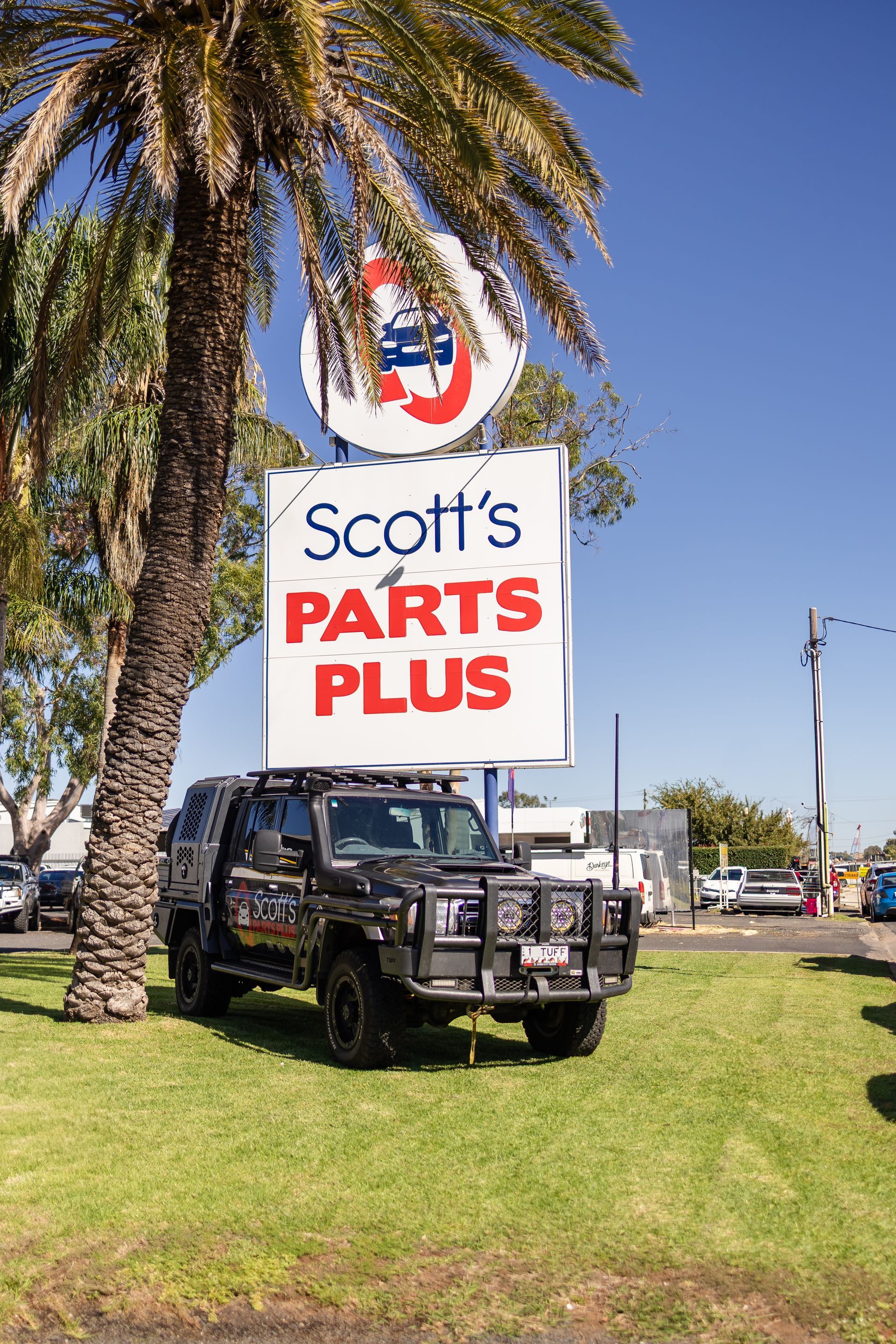 A White Car Is Parked In Front Of A Scott 's Parts Plus Sign — Scott's 4WD Parts Plus In Dubbo, NSW