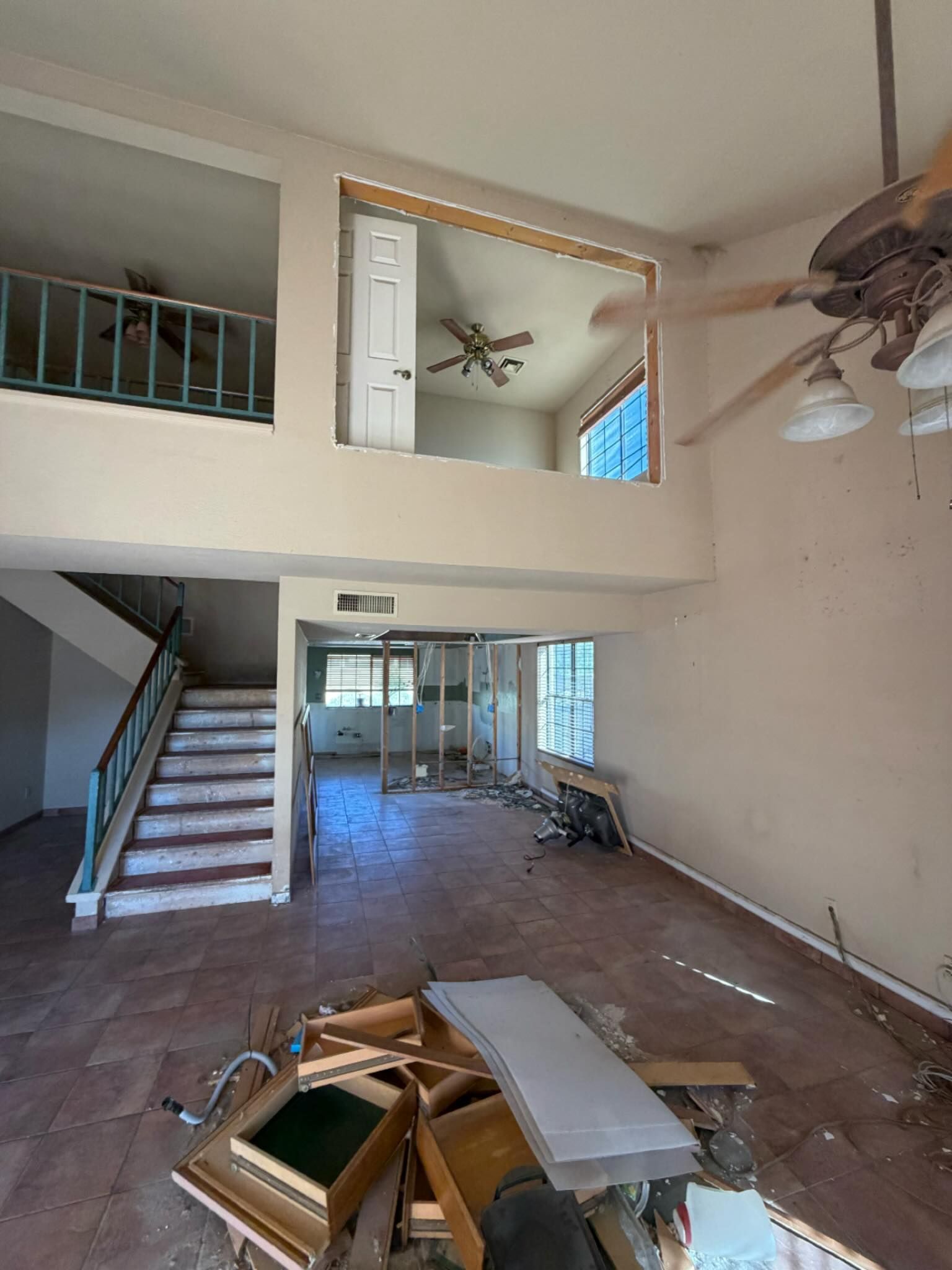 Interior of a home undergoing renovation; exposed beams, debris, and partial walls.