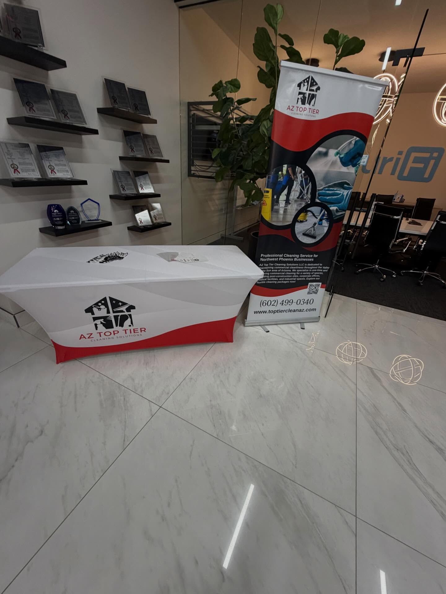 A promotional display in an office with a branded table cover and banner, white and red accents.