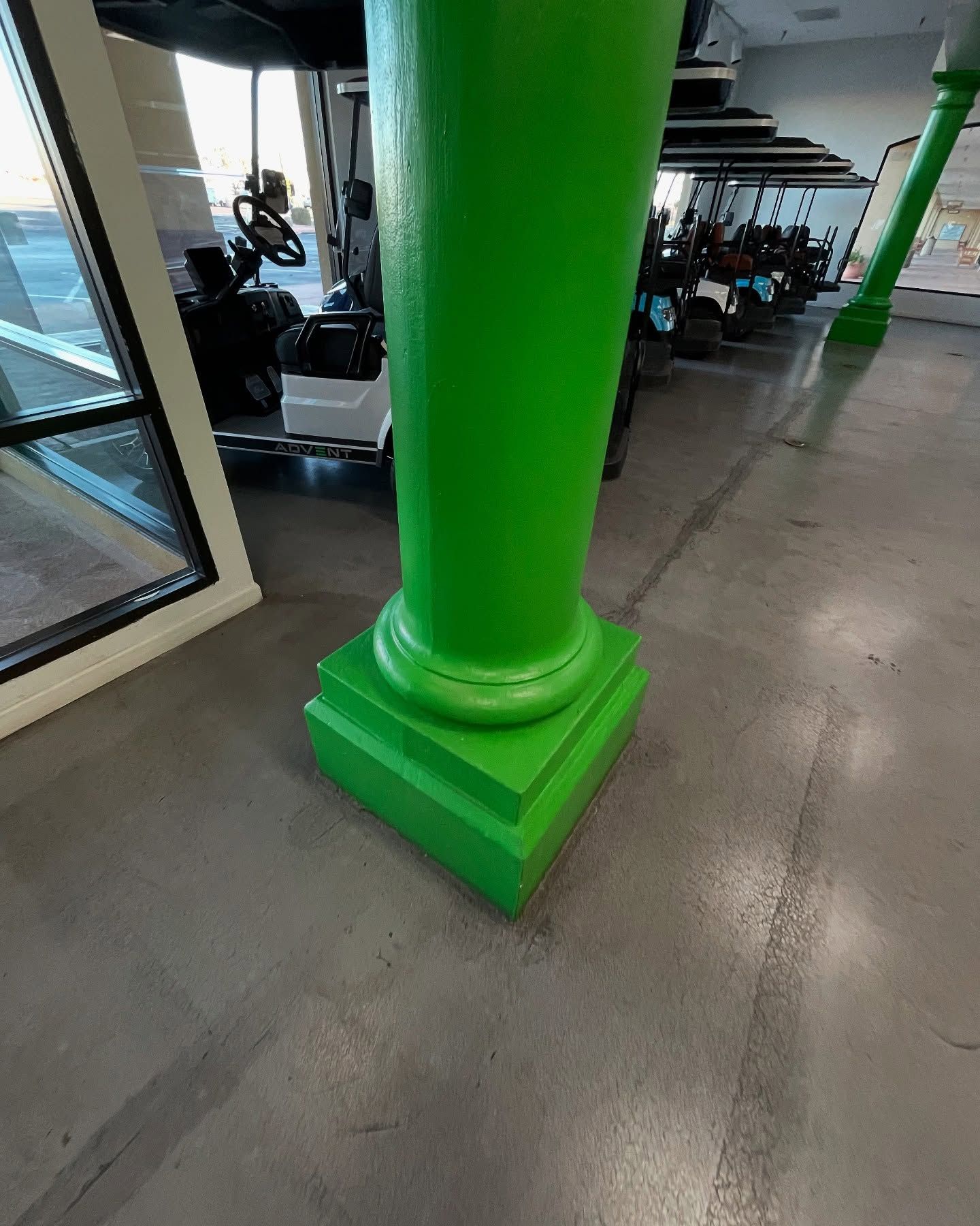 Green column with a square base, inside a building.