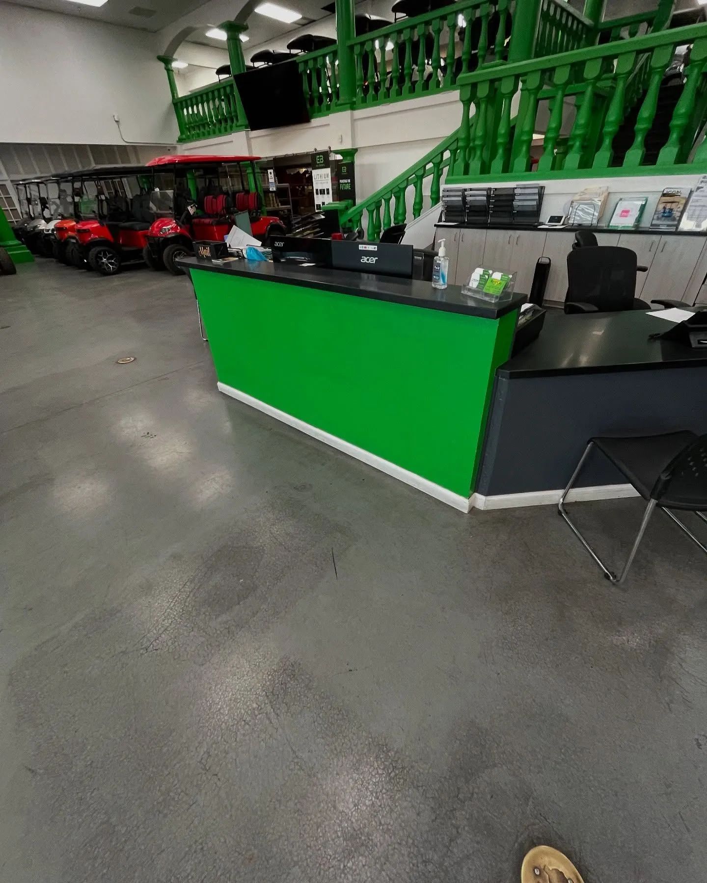 Green and black reception desk in a golf cart dealership, golf carts in background.