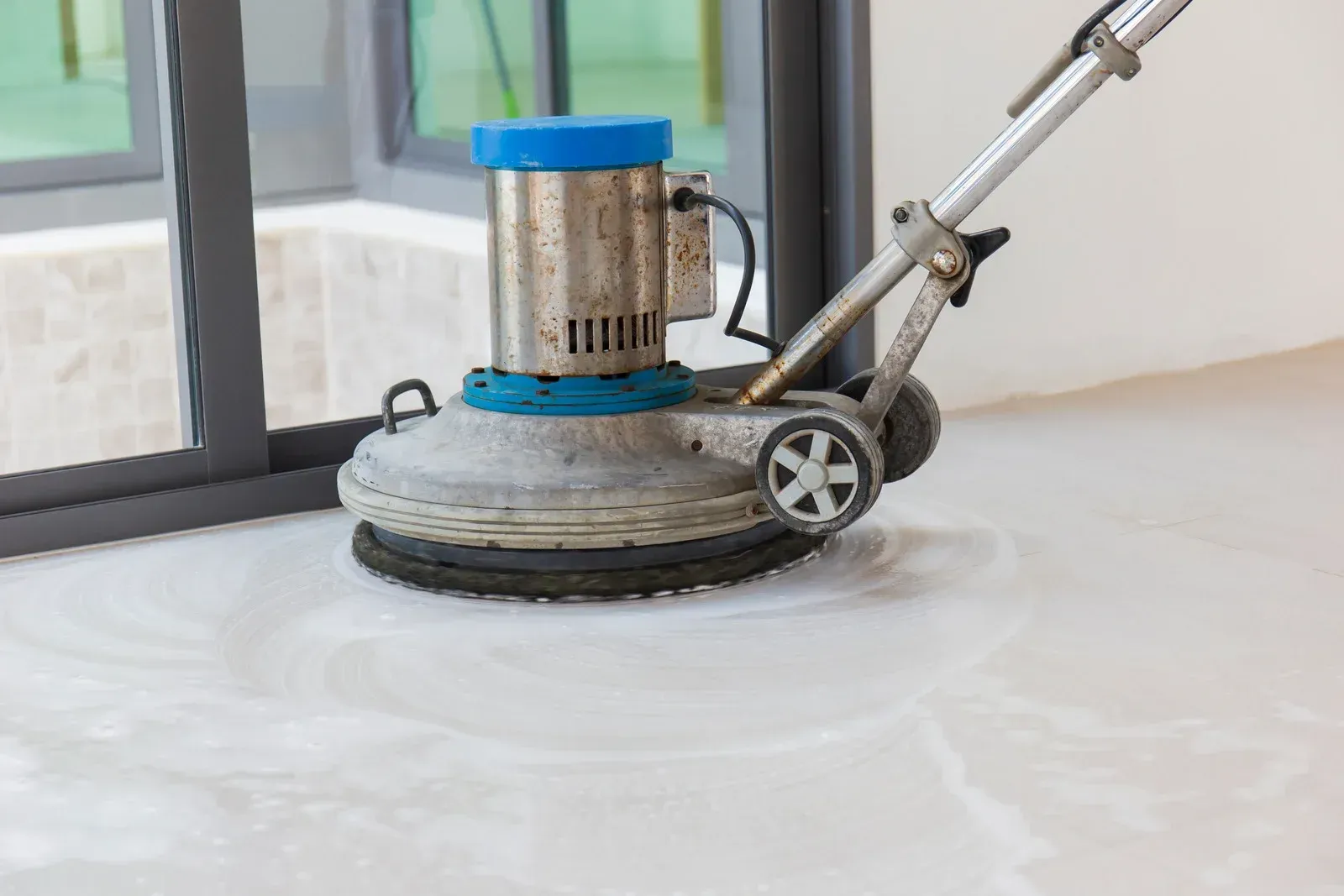 Woman cleaning floor, green bucket of cleaning supplies in foreground.
