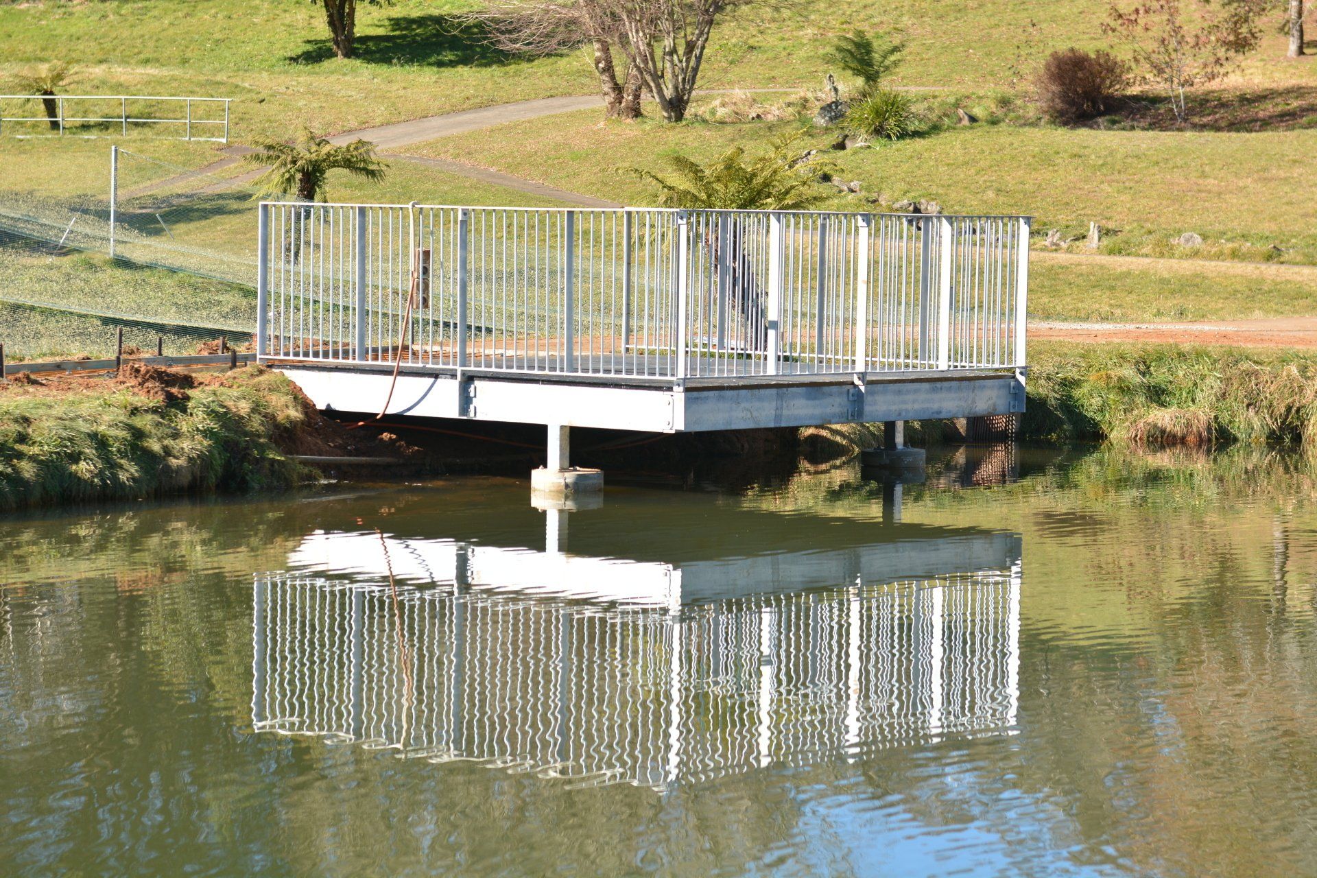 a steel ramp over a body of water with trees in the background