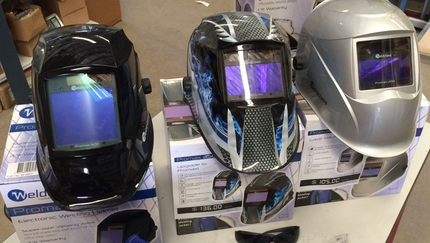 three welding helmets are sitting on top of each other on a table .