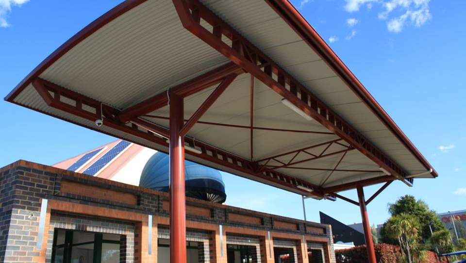 gazebo made with red steel next to building outside