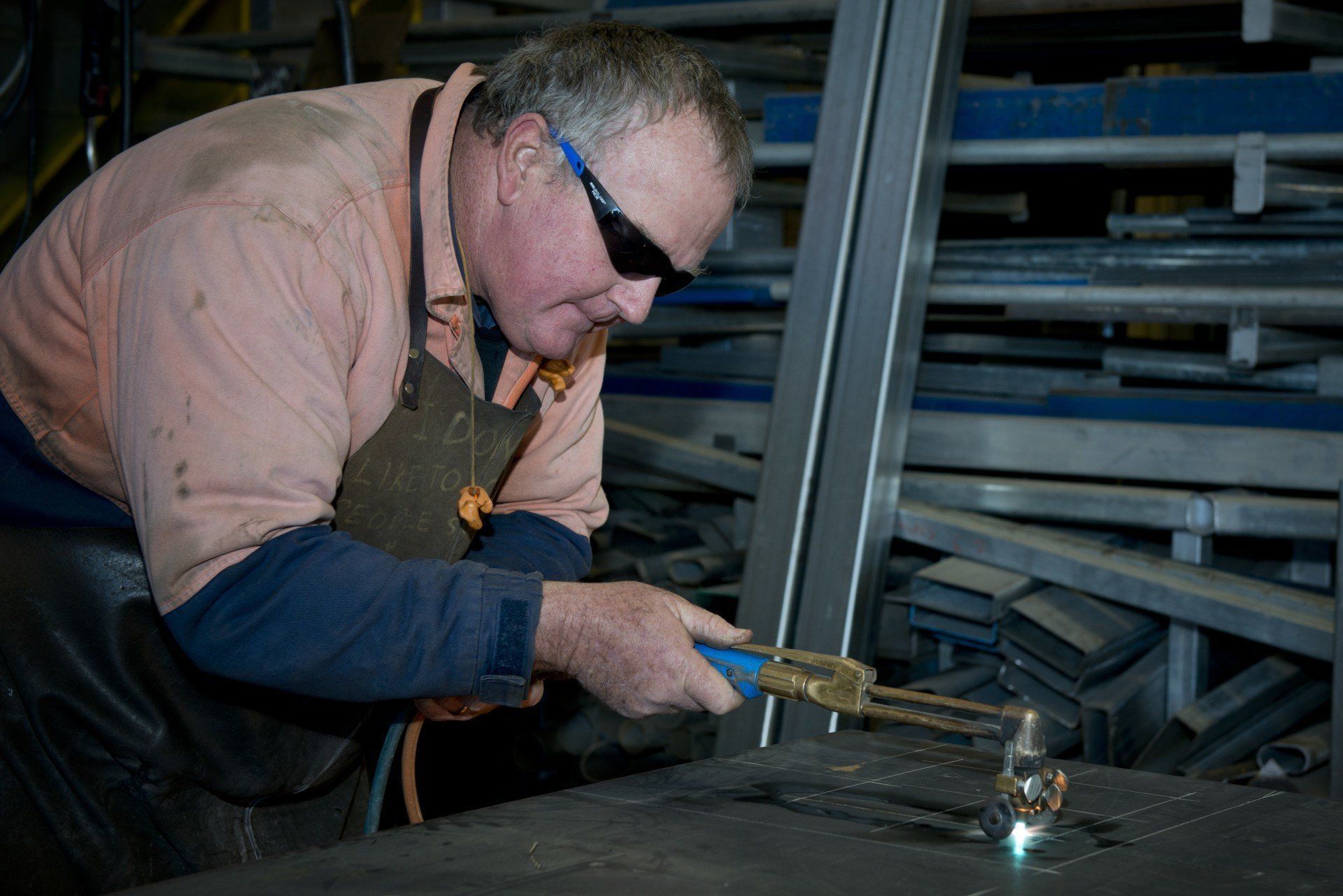 a man wearing safety glasses is welding a piece of metal .