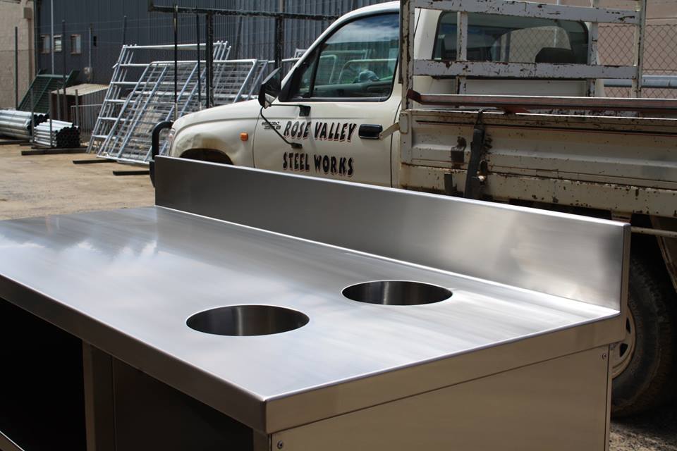 A stainless steel bench with a truck in the back