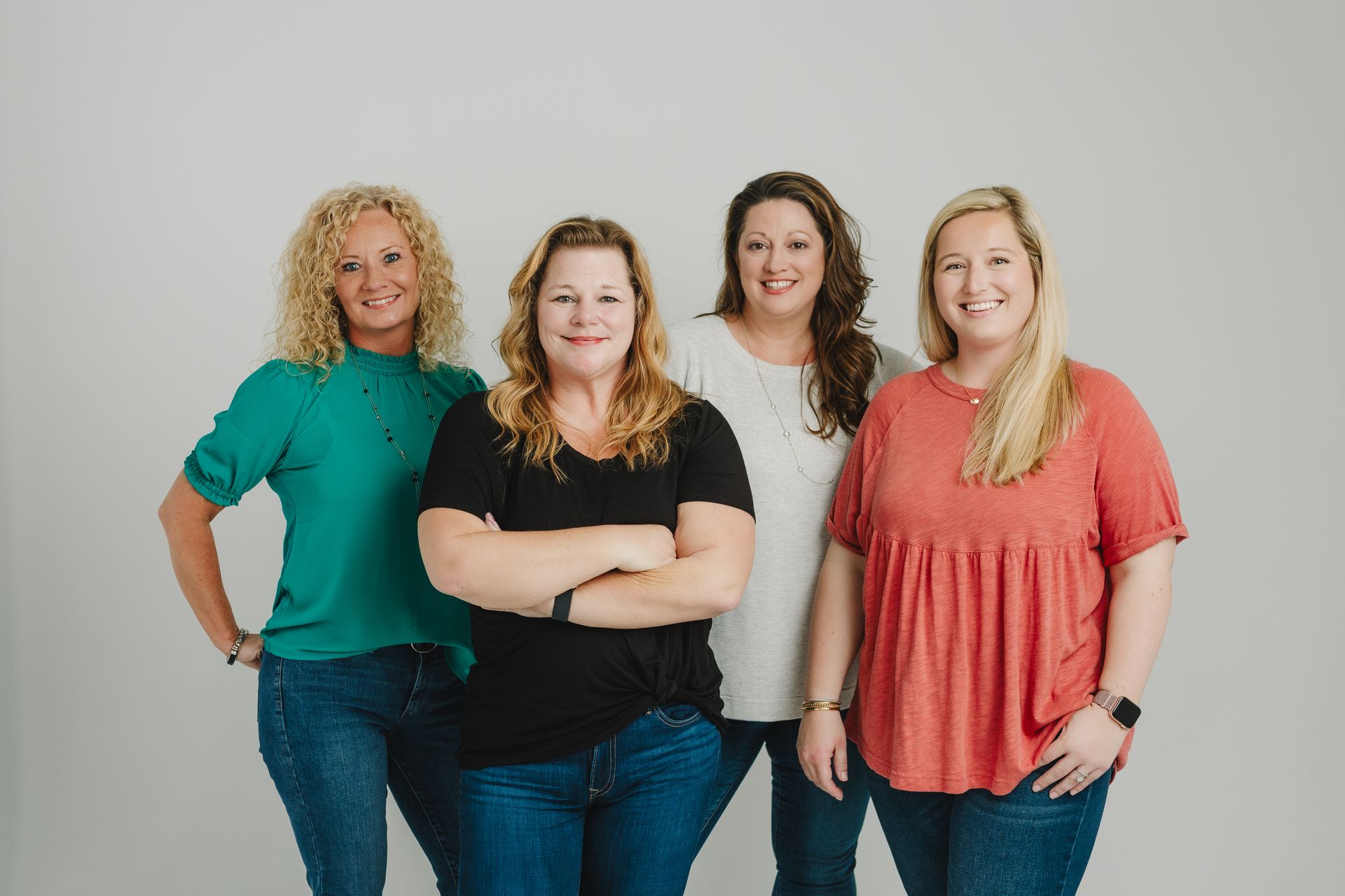 Four women are standing next to each other with their arms crossed.