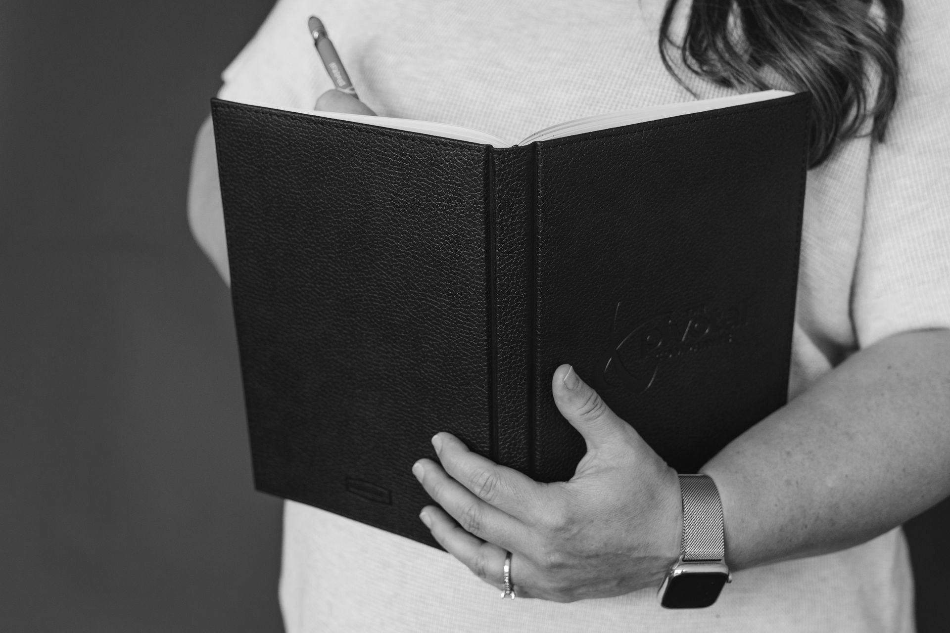 A woman is holding a book and a pen in her hands.