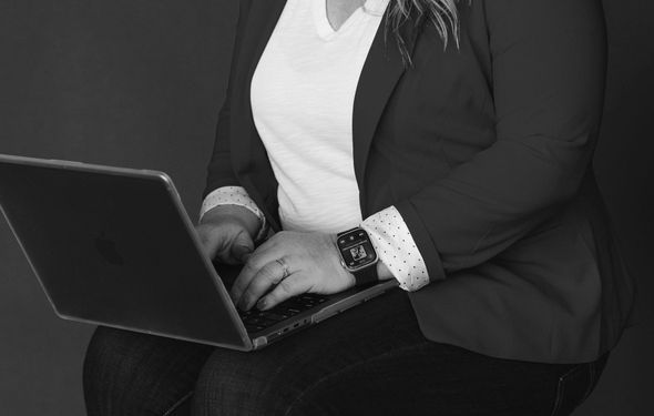 A woman is sitting down using a laptop computer.