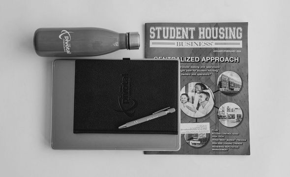 A black and white photo of a laptop , notebook , water bottle , and student housing magazine.