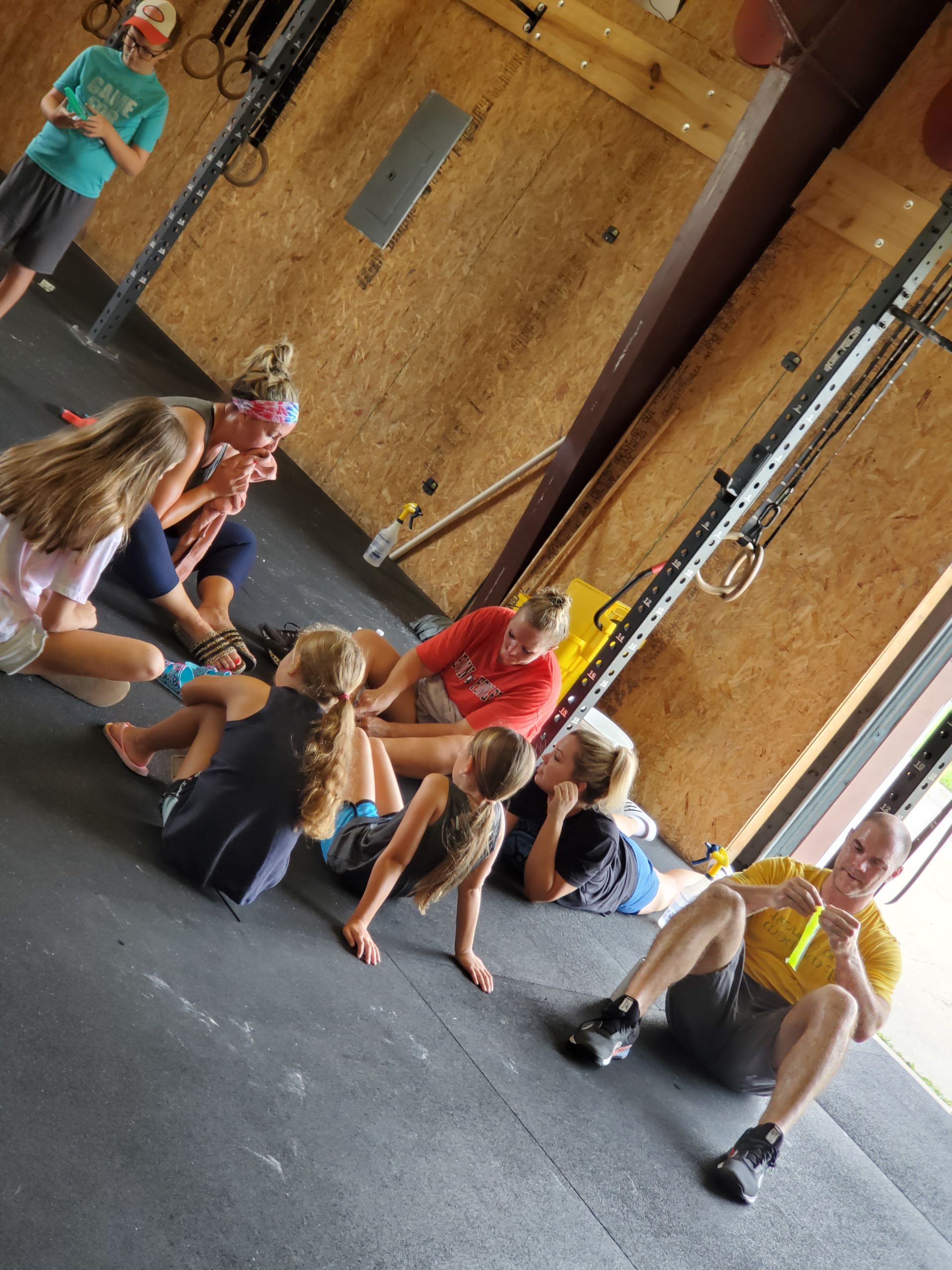 Group of people exercising on a the floor of a gym in Lavon, TX, some seated, others leaning.