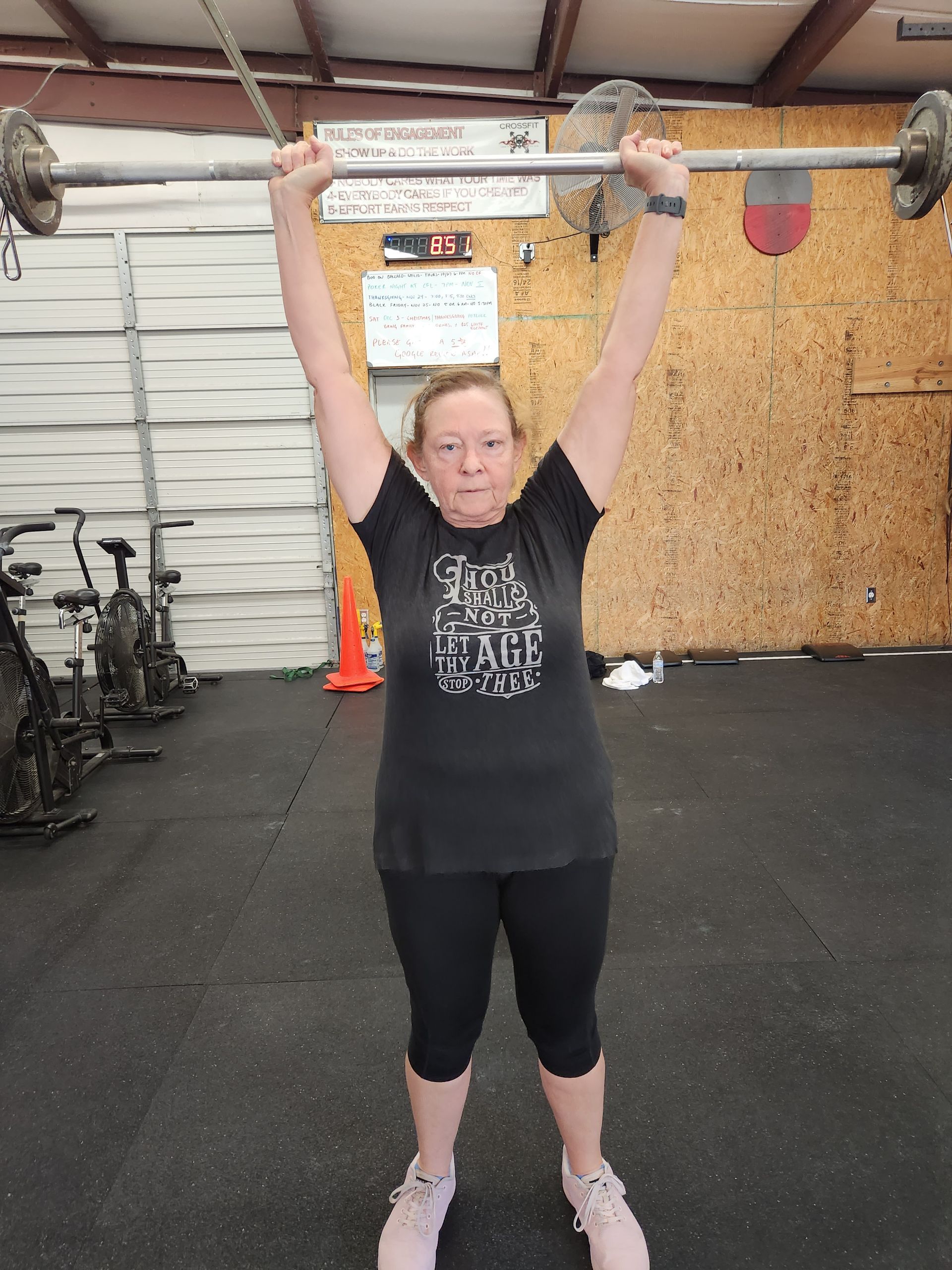 Woman in black workout clothes lifting barbell overhead in a CrossFit gym in Lavon, TX