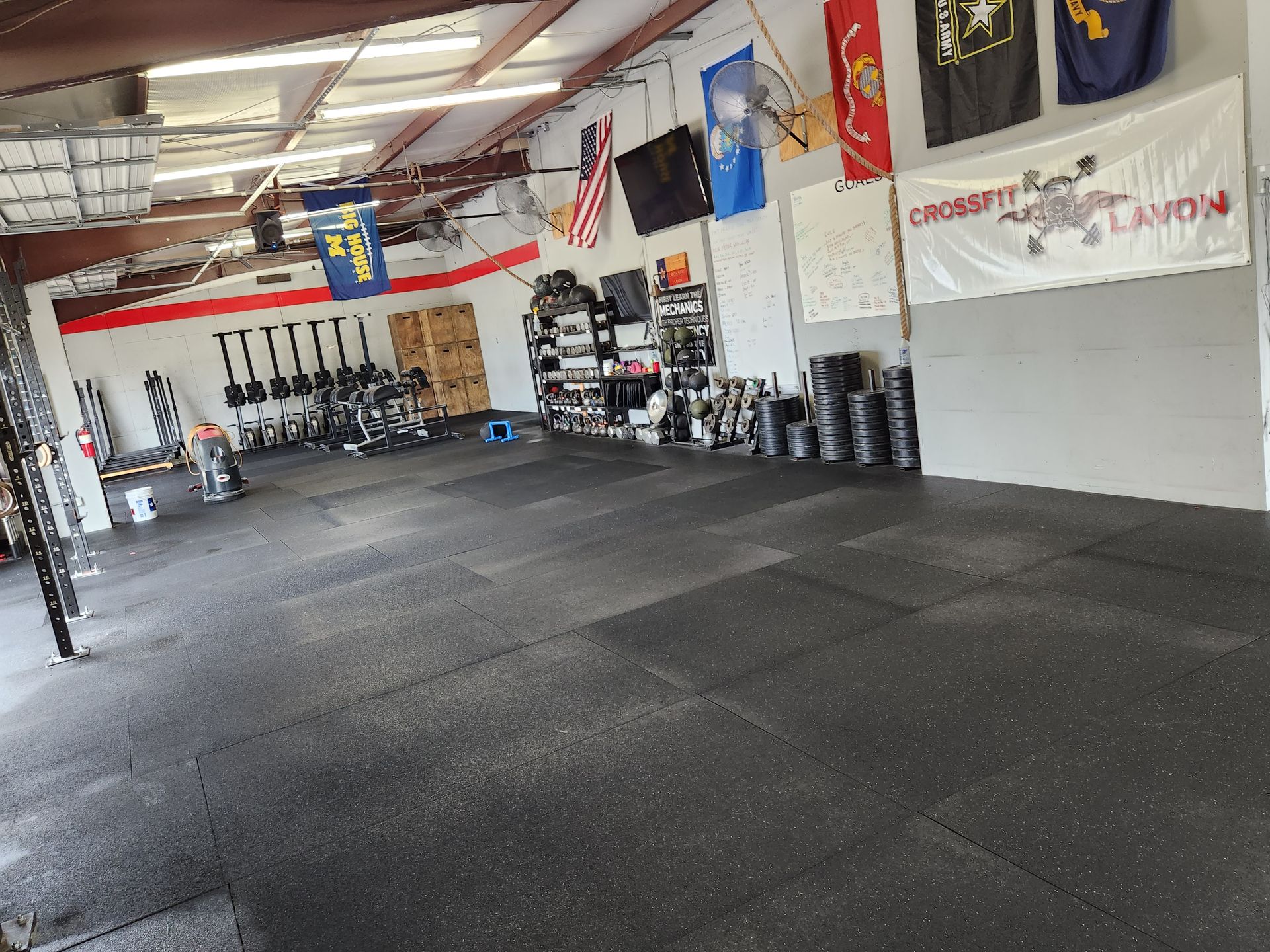 Interior of a CrossFit gym in Lavon, TX, equipment and weights are on the floor. Flags and banners hang from the ceiling.