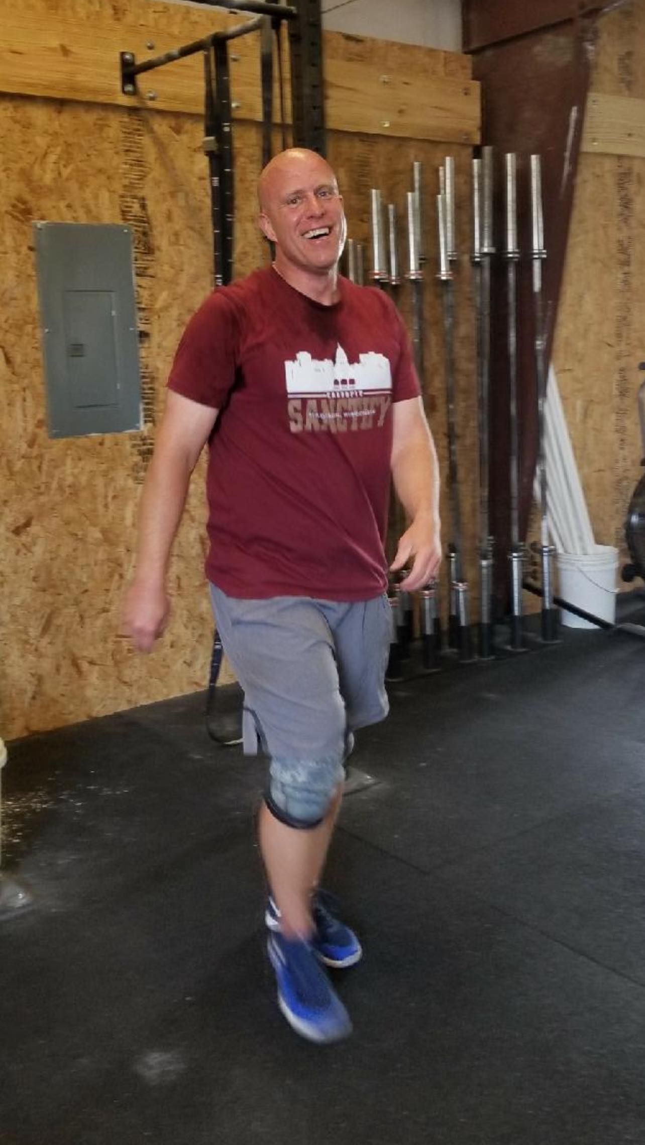 Man in maroon shirt and gray shorts laughing in a gym in Lavon, TX.