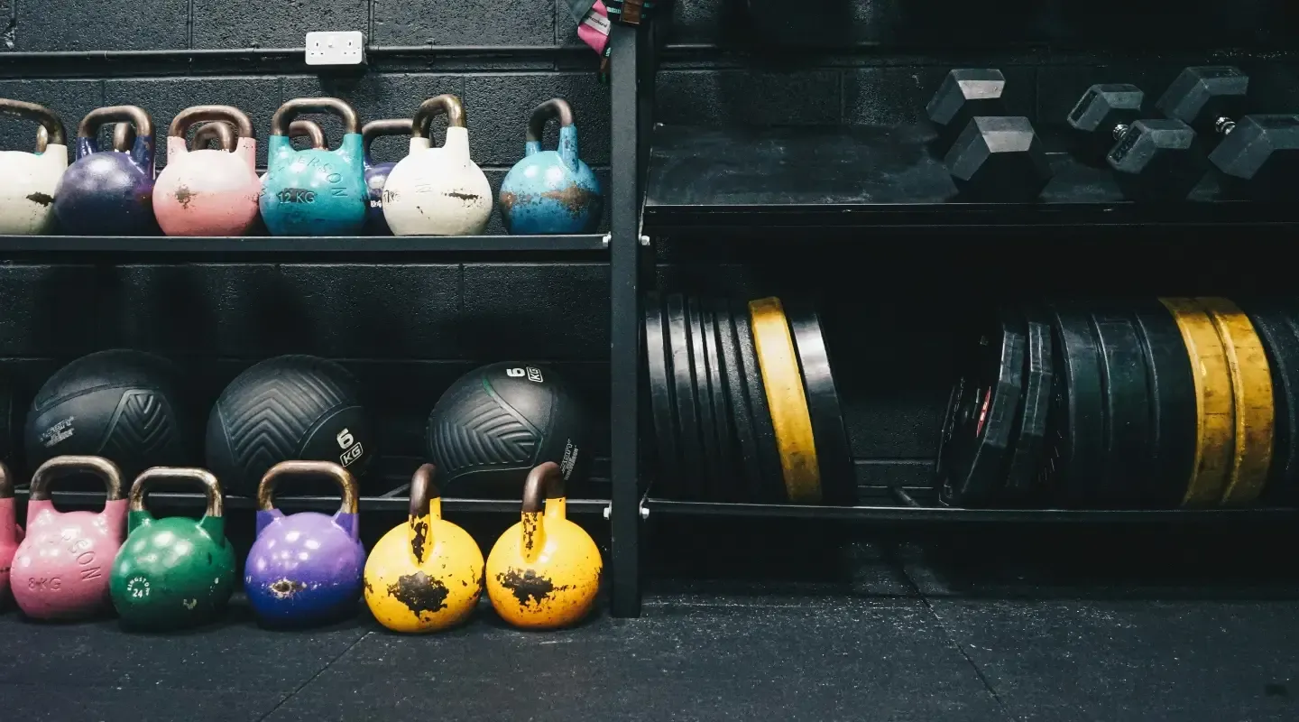 Shelves stocked with colorful kettlebells, medicine balls, weight plates, and dumbbells at CrossFit Lavon.