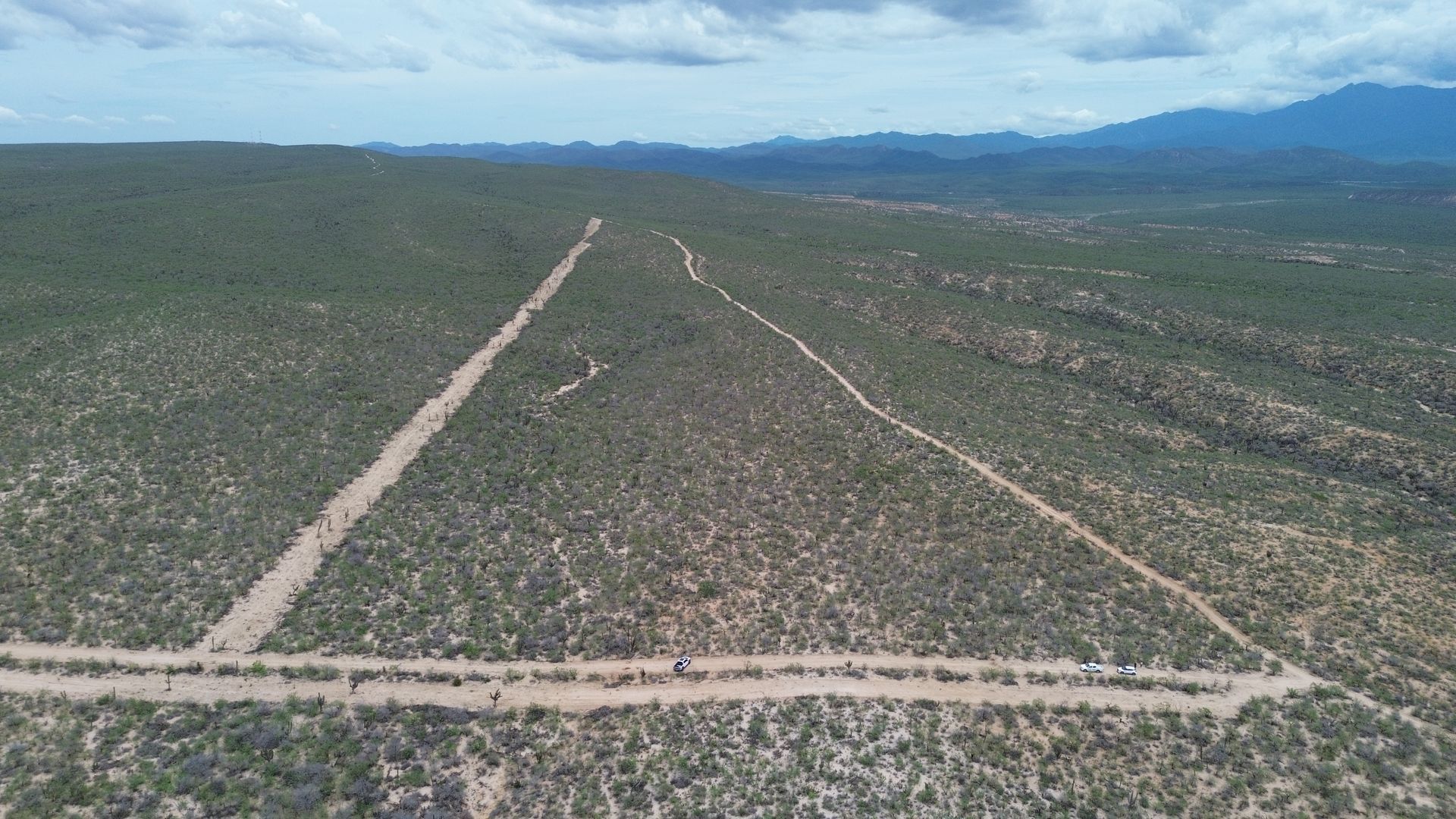 Aerial view of a wide, dirt trail forming a triangle shape through a desert landscape with sparse vegetation.