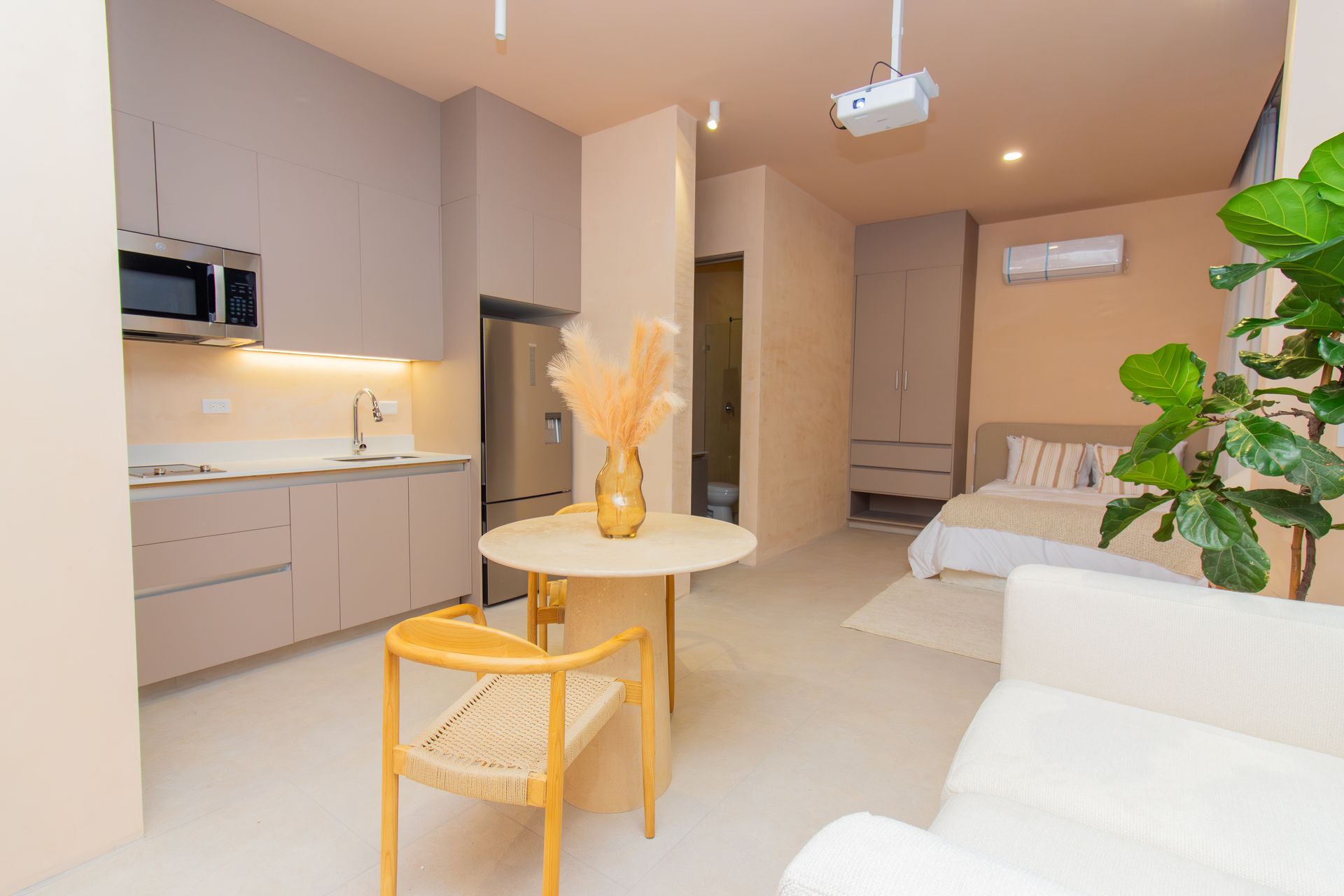 Small studio apartment with kitchen, dining area, and bedroom, light color scheme.