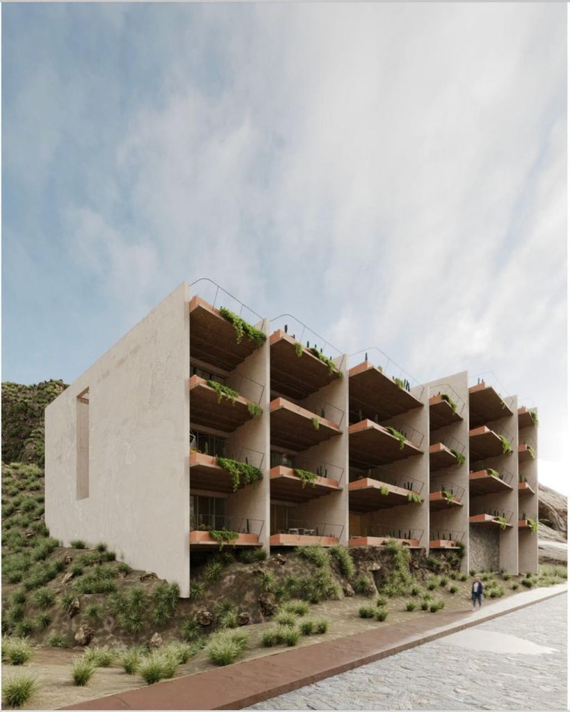 Modern building with stacked wooden balconies, greenery, and person walking nearby on a hillside road.