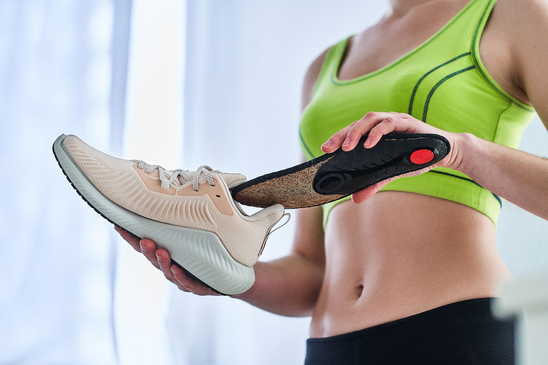 A woman is holding a pair of shoes and a pair of insoles.