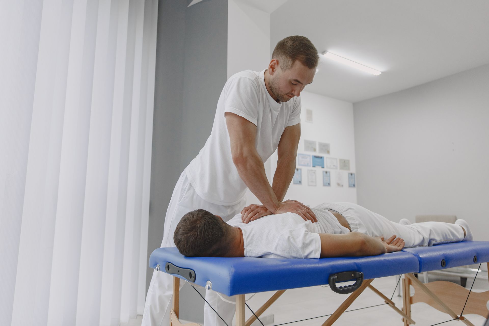 A man is giving a man a massage on a blue table.