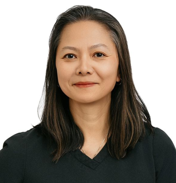 A professional standing against a white background, wearing a black scrub top and pants with one hand on their hip.