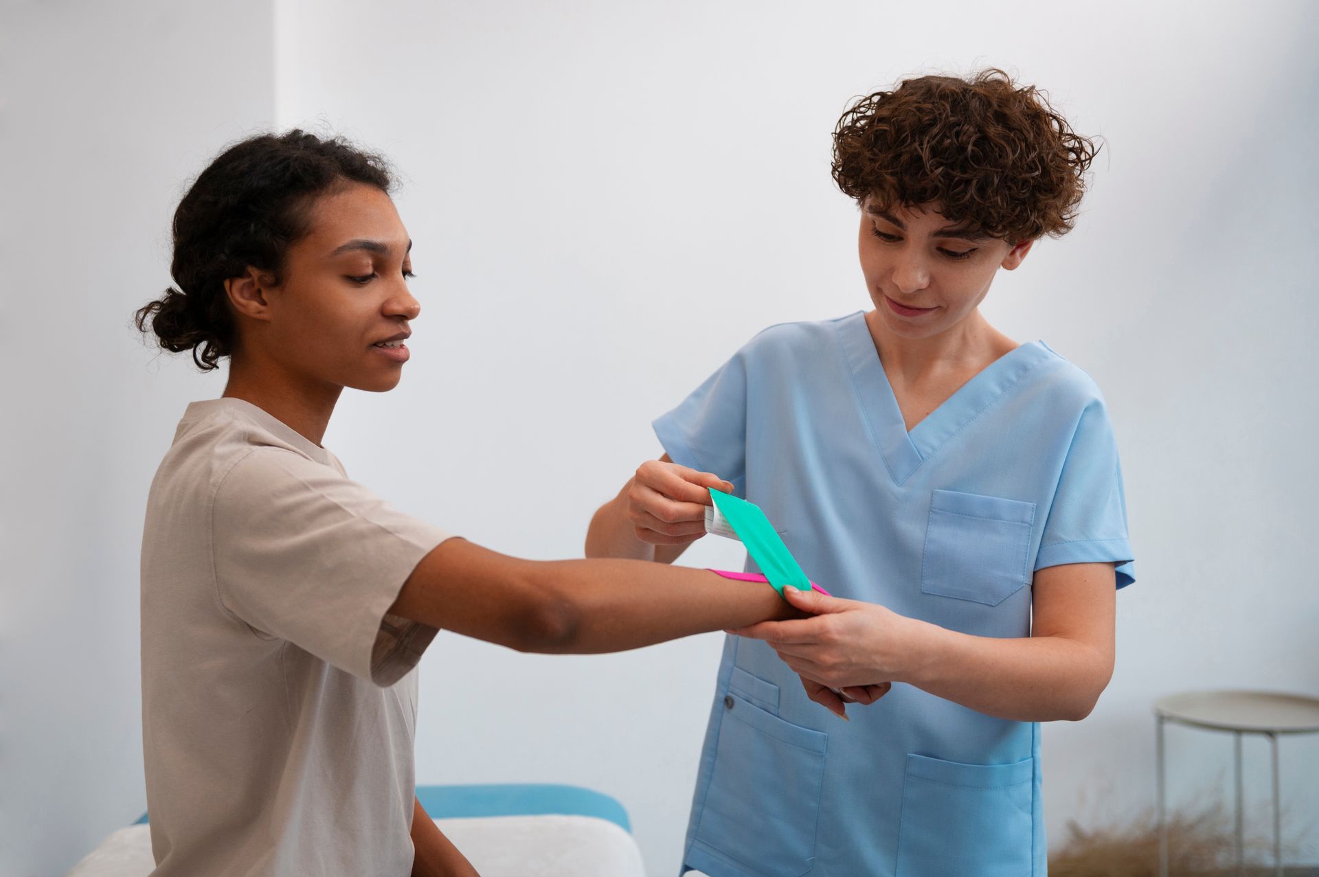 A nurse is putting a bandage on a patient 's wrist.