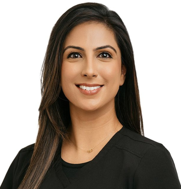 A person with long dark hair, wearing a black scrub top and long sleeves, smiling against a plain white background.