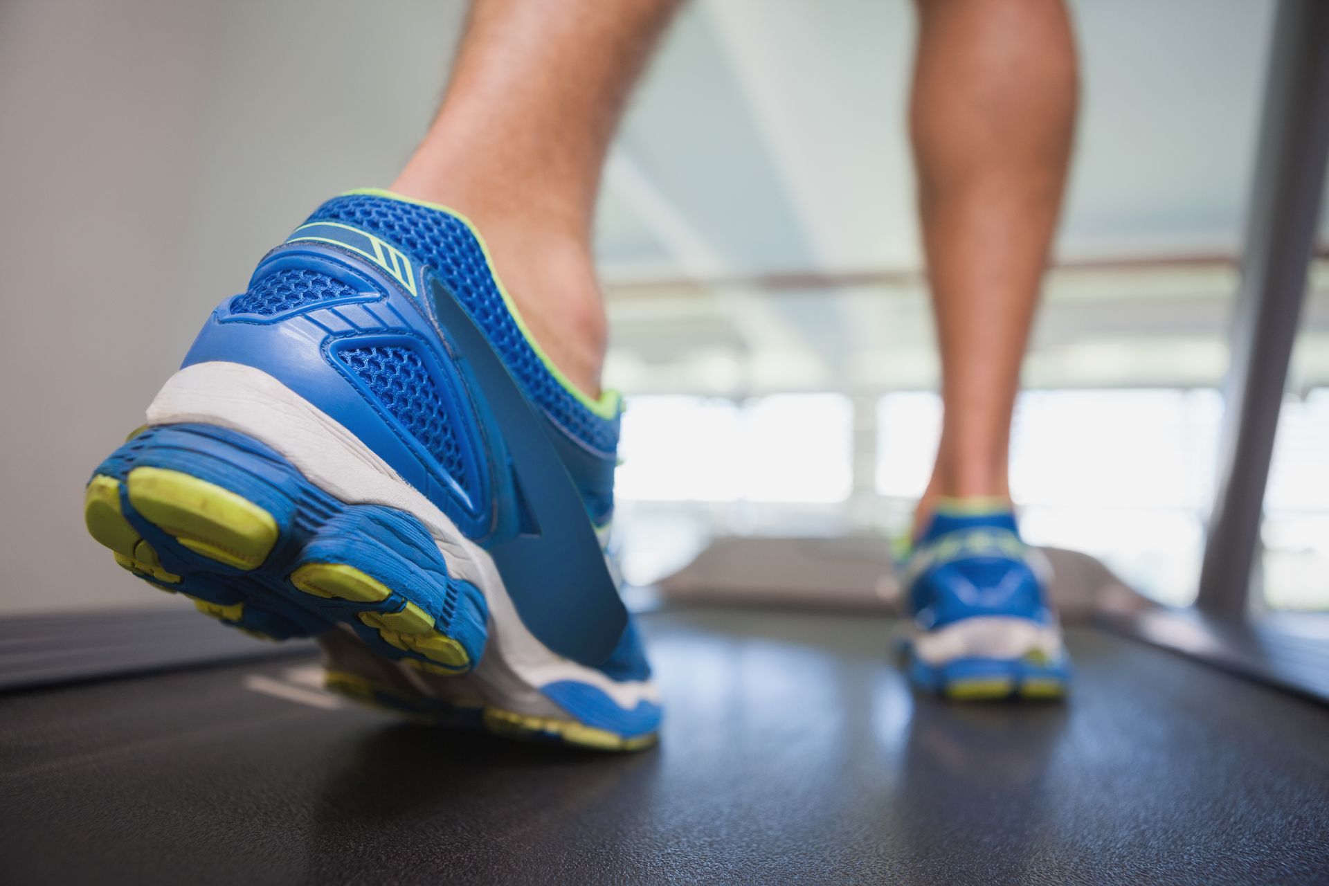 A person is walking on a treadmill in a gym.