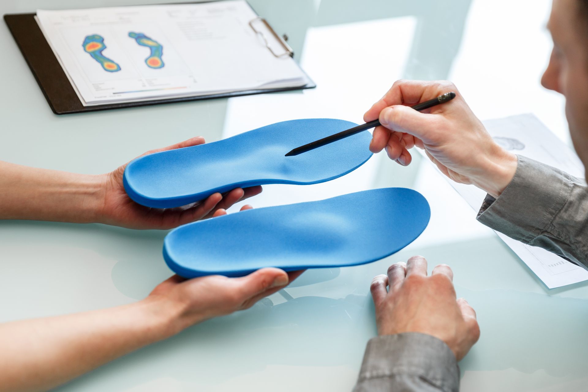 A person is holding a pair of blue insoles in their hands.