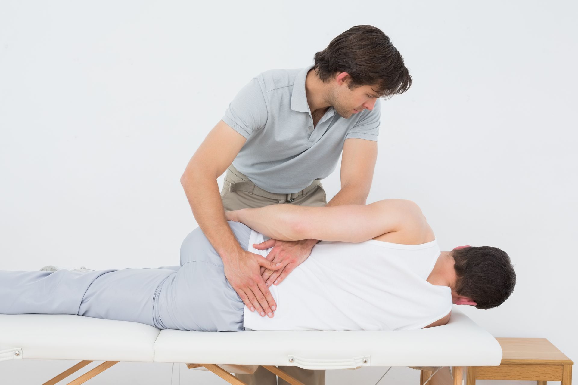 A man is laying on a table getting a massage from a doctor.