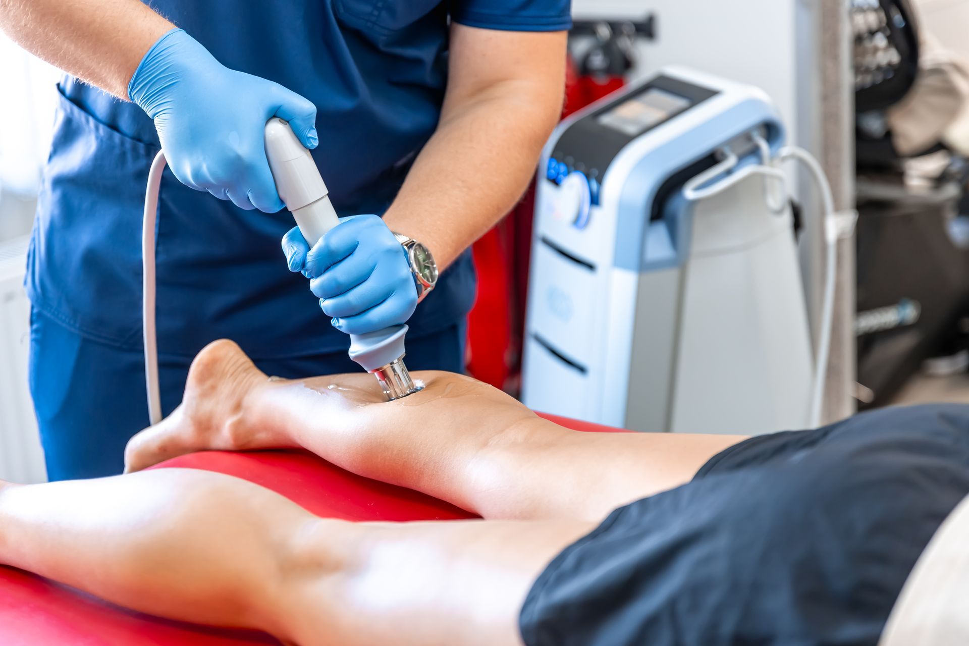 A doctor is using a machine on a patient 's leg.