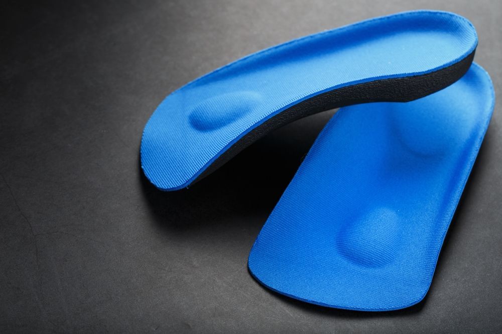 A pair of blue insoles are sitting on top of each other on a black surface.