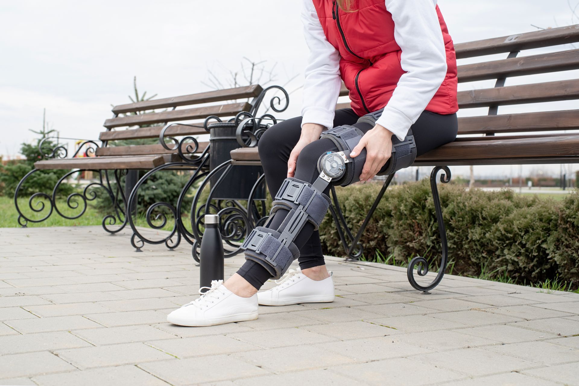 a woman is sitting on a bench with a knee brace on her leg .
