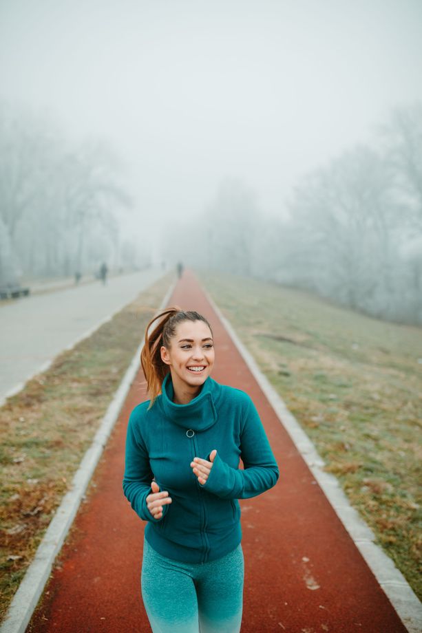 A woman is running on a track in the fog.