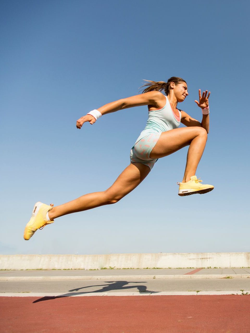 A woman is jumping in the air on a track.